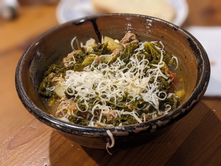 Kale Kielbasa Soup topped with Parmesan cheese